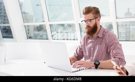 Hipster businessman at the office working with a laptop with his team Stock Photo