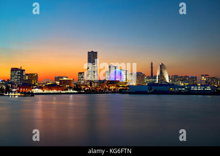 Yokohama, Japan skyline at dusk with the city lights and orange sky