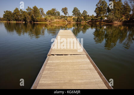 wooden pier in the lake with florest trees scenery background. Stock Photo