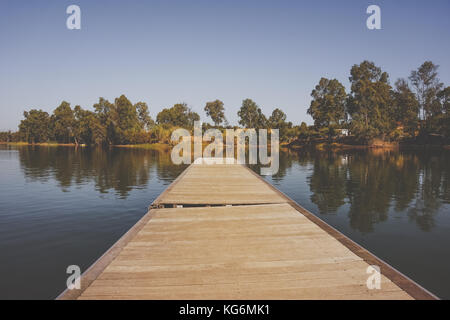 wooden pier in the lake with florest trees scenery background. Stock Photo