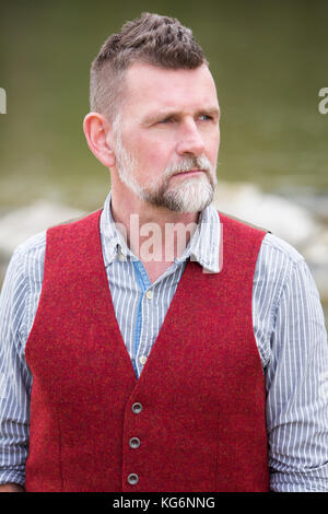 portrait of handsome man in his 50s wearing a shirt and red vest Stock Photo