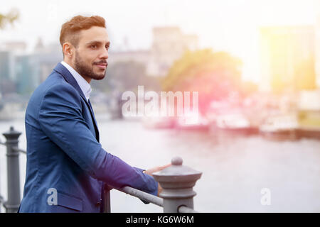handsome dark-haired businessman standing by the river Stock Photo