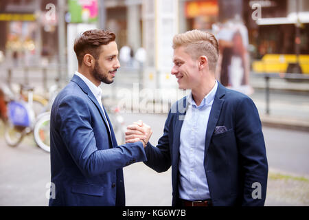 two handsome businessmen greeting each other in the street Stock Photo