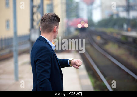 blond man checking the time and waiting for the train Stock Photo