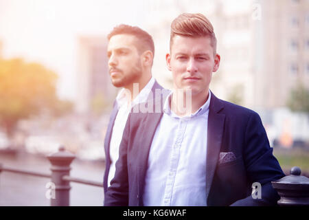 portrait of two handsome businessmen standing outside and waiting Stock Photo