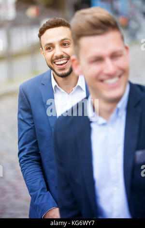 two handsome businessmen standing outside and laughing Stock Photo