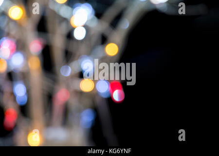 Multicolor defocussed bokeh Christmas lights on branches against a black background with copyspace Stock Photo