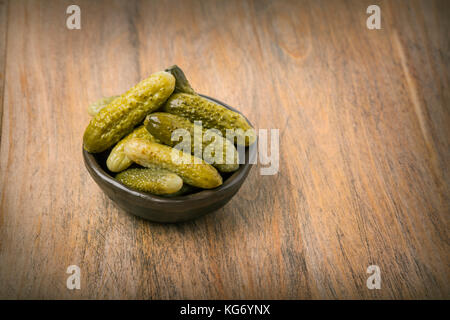 Pickled cucumbers in a wooden bowl  against dark rustic background Stock Photo