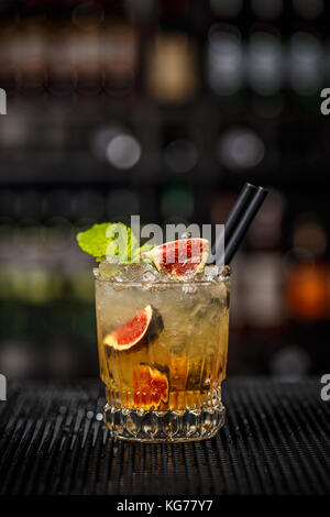 Glass of iced refreshing cocktail with fig served on bar counter Stock Photo