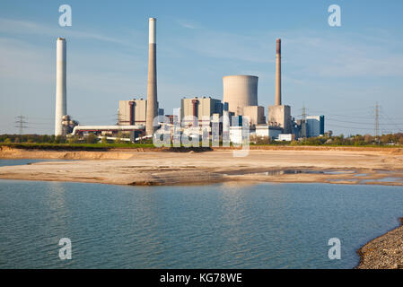 View over gravel plant lake to a giant coal power station with slight reflection. Stock Photo