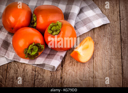 Delicious fresh persimmon fruit on wooden table. Stock Photo