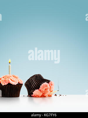 Smashed cupcake in row of cupcakes with candles on blue background Stock Photo