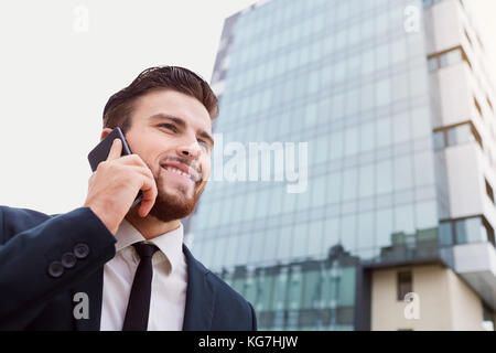 Businessman speaks on the phone outdoors Stock Photo