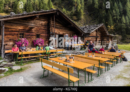 Habachtal, Austria - September 28, 2017: Thuringer Hutte with terrace and hiking tourists, old cabins in the valley with the Smaragdweg, Austria. Stock Photo