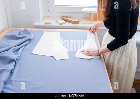 Seamstress hands on the work table with pattern. Style and design development and creating garment, clothes sew and repair service, seamstress at work Stock Photo