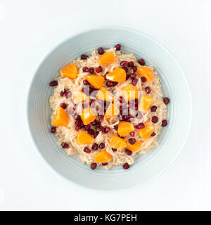 Overnight Oats with grated pear, pomegranate and clementine for autumn and winter in a blue porcelain bowl. Top view. Stock Photo