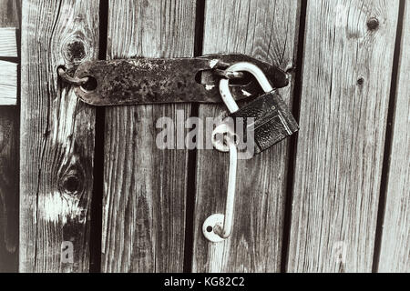 Old rusty padlock on a decaying fence. Security concept: open padlock on wooden wall. Black and white colors. Stock Photo