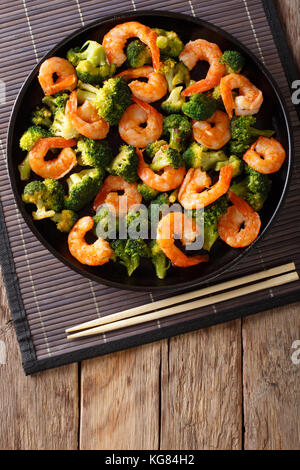 Stir frying shrimp with broccoli closeup on a plate. Vertical top view from above Stock Photo