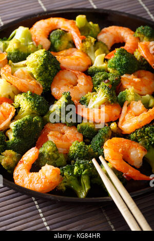 Freshly cooked prawns with broccoli close-up on a plate. vertical