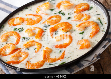 Tiger prawns with spinach and garlic in creamy cheese sauce close-up on a plate on a table. horizontal Stock Photo