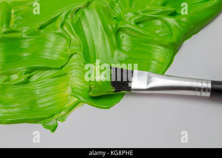 Green paint and art brush with thick glossy strokes on white paper. Eco friendly concept Stock Photo