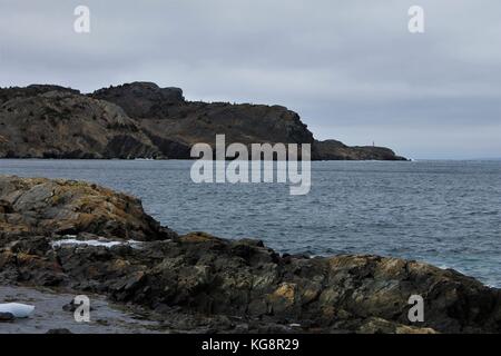 Looking from the beach across the water to the far side of the bay, Brigus, Newfoundland and Labrador, Canada. Rocky coastline, some ice in bay. Stock Photo