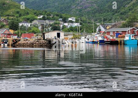 Fishing boats tied up at the wharf, Petty Harbour, Newfoundland Labrador. Fishing sheds, stages, other fishing gear, and houses also in image. Stock Photo