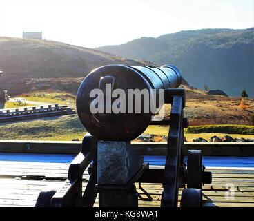 Cannon on Signal Hill, St. John's, Newfoundland and Labrador, Canada. Sun reflecting of the barrel, frost on the ground, Queen's Battery in background Stock Photo
