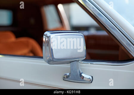 Chrome and white lacquered wing mirror on a classic vintage car viewed with the side window in the background and copy space Stock Photo