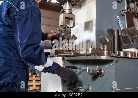 Close-up of a male auto mechanic in blue uniform works on an automatic welding machine for the repair of cardan shafts  for repairing cars and trucks Stock Photo