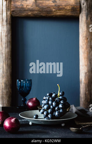 Black grapes on vintage silver tray still life. Vertical composition Stock Photo