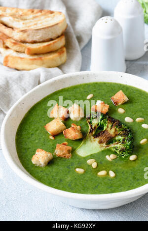 Broccoli cream soup with croutons and roasted pine nuts in white bowl. Healthy green food, dieting, healthy lifestyle concept Stock Photo