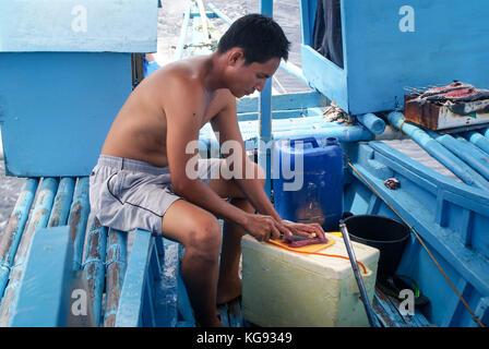 Puerto Princesa, Philippines - May 9, 2009: Fisherman fillets the freshly caught tuna before serving it raw to tourists on a whale shark tour near the Stock Photo