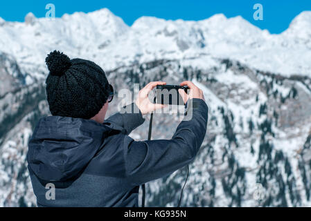 Female tourist taking panoramic picture of beautiful winter mountain landscape with compact digital camera Stock Photo
