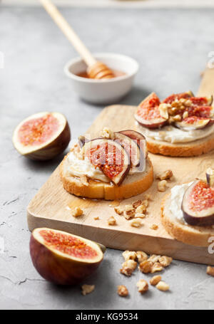 sandwiches with figs, ricotta, honey and walnuts on a gray background Stock Photo