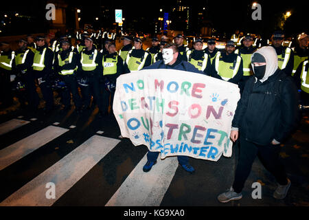 London, UK. 5th Nov 2017. Police cordon the street during the 'Million Mask March' demonstration organized by Anonymous inspired activists. A protester wearing Anonymous V for Vendetta mask is holding a placard reading: 'No more deaths on our streets. #opsafewinter'. Credit: ZEN - Zaneta Razaite / Alamy Live News Stock Photo