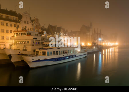Ships moored by Long Embankment on Motlawa River in Old Town of Gdansk, Poland at misty night. Stock Photo