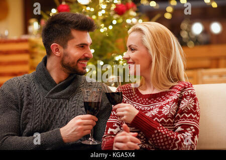 Loving couple celebrating Christmas toasting with glasses of red wine Stock Photo