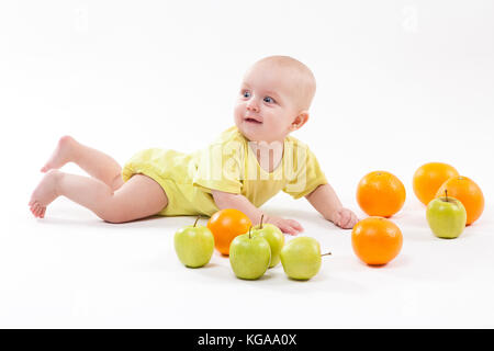 cute surprised baby looks at green apple on a white background Stock Photo