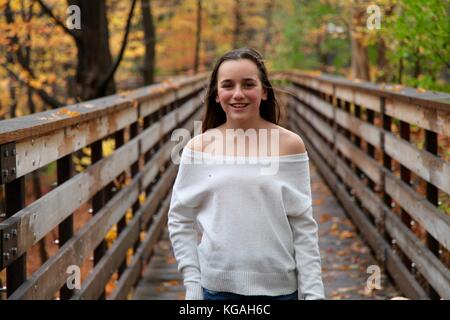 Portrait of a young teenage girl smiling and looking at the camera outdoors in a forest Stock Photo