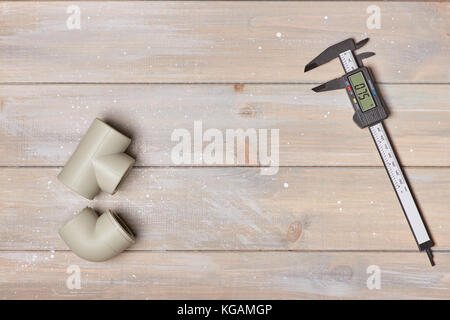 Electronic calipers and two plastic pipes lie on a wooden table. In the middle of an empty seat Stock Photo