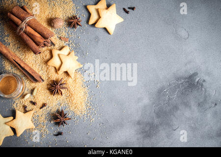 Christmas spices, gingerbread cookies and baking ingredients on grey concrete background. Cinnamon, anise stars, nutmeg, cardamon, cloves, brown sugar Stock Photo