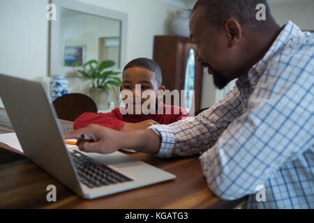 Father and son using laptop in living room at home Stock Photo