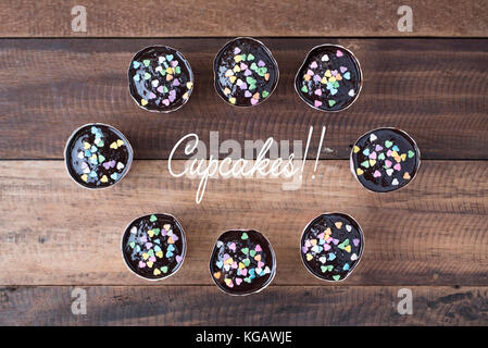 homemade cupcakes on wooden table (top view) with "cupcakes!!" word Stock Photo