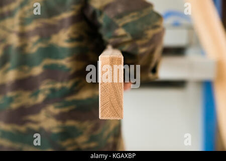 Rear view of a worker carrying a new wooden beam in workshop Stock Photo
