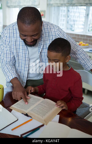 Handsome father helping son with homework at table Stock Photo - Alamy