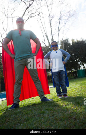 Son and father pretending to be a superhero in garden Stock Photo