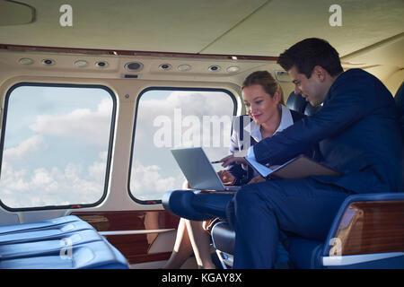 Businessman And Businesswoman Working On Laptop In Helicopter Cabin Stock Photo