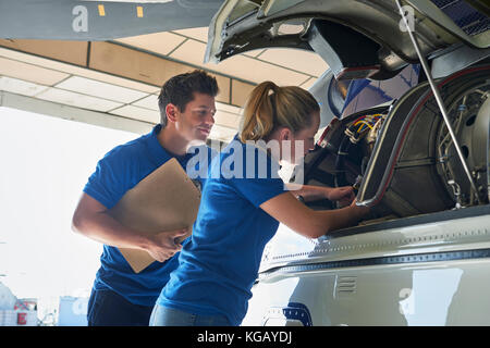Aero Engineer And Apprentice Working On Helicopter In Hangar