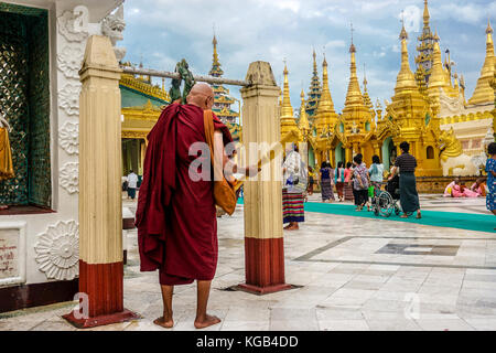 Monk rings gong at Shwedagon Pagoda (officially named Shwedagon Zedi Daw) and also known as the Great Dagon Pagoda.  A  gilded stupa located in Yangon Stock Photo